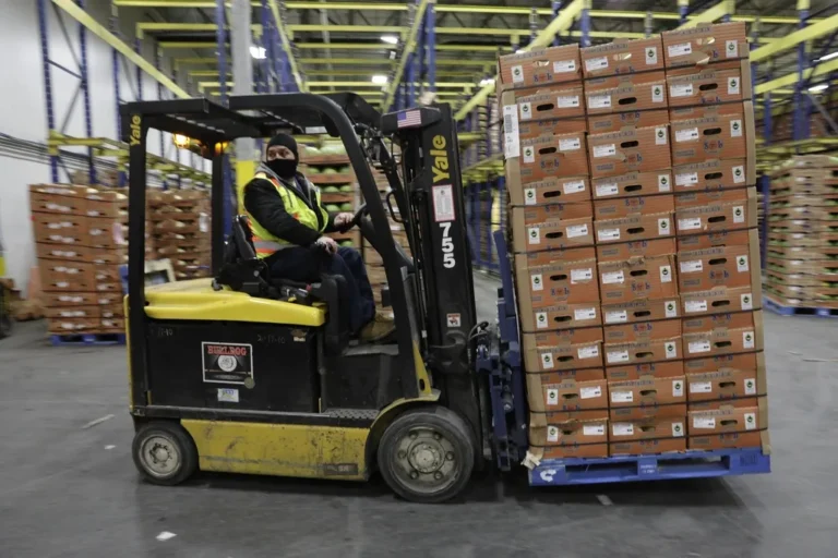 A forklift moving a loaded pallet inside a commercial warehouse