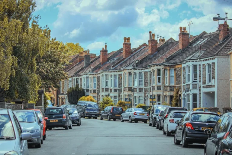 Cars parked along a street of classic terraced townhouses